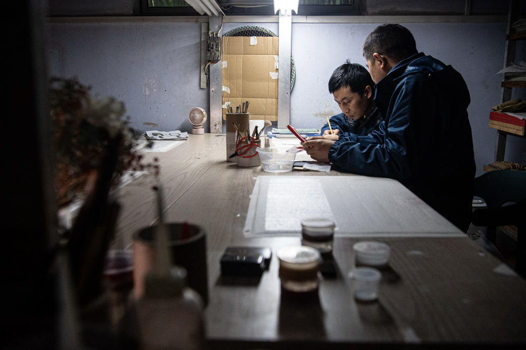在重慶萬州譚木匠木梳非遺工坊內，崔國文（左）在師父俞達洪的指導下進行大漆工藝創作（1月5日攝）。