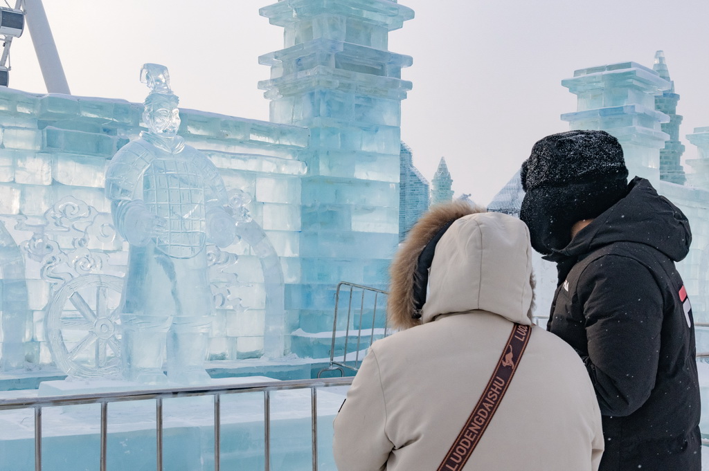 1月23日，在哈尔滨冰雪大世界园区，游客在“冰马俑”冰雕前游玩。