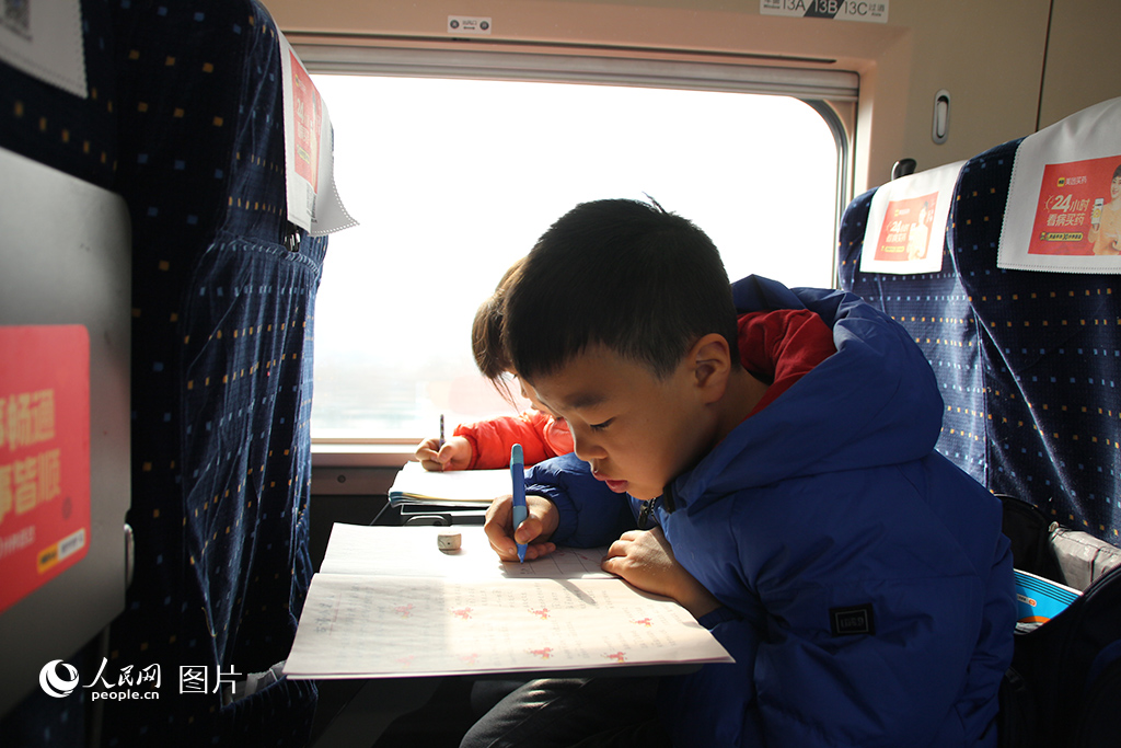 1月25日，西安北開往深圳北的G828次列車上，兩位小朋友正在寫寒假作業。人民網記者 賈凱璐攝