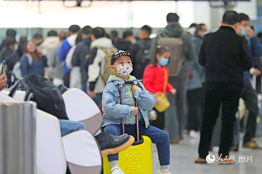 2024年1月25日，廈門北站候車室裡的一位小乘客坐在行李箱上東張西望，等待著回家的列車。人民網記者 陳博攝