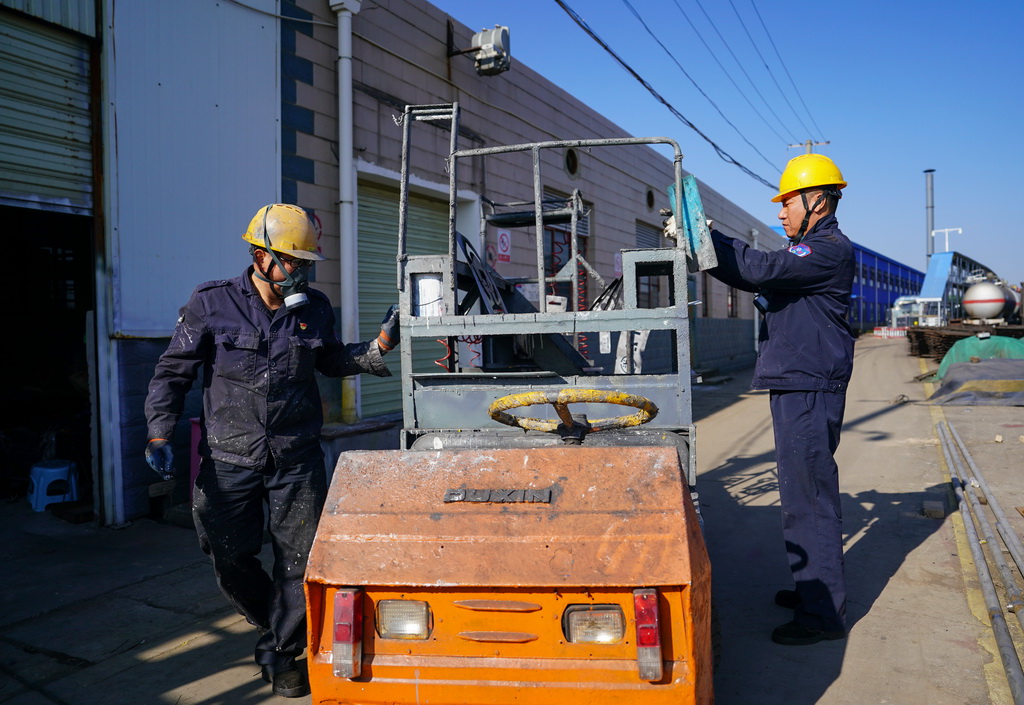 2月1日，張樹紅（左）和搭檔賈童整理電瓶車上的工具准備出發去車間工作。