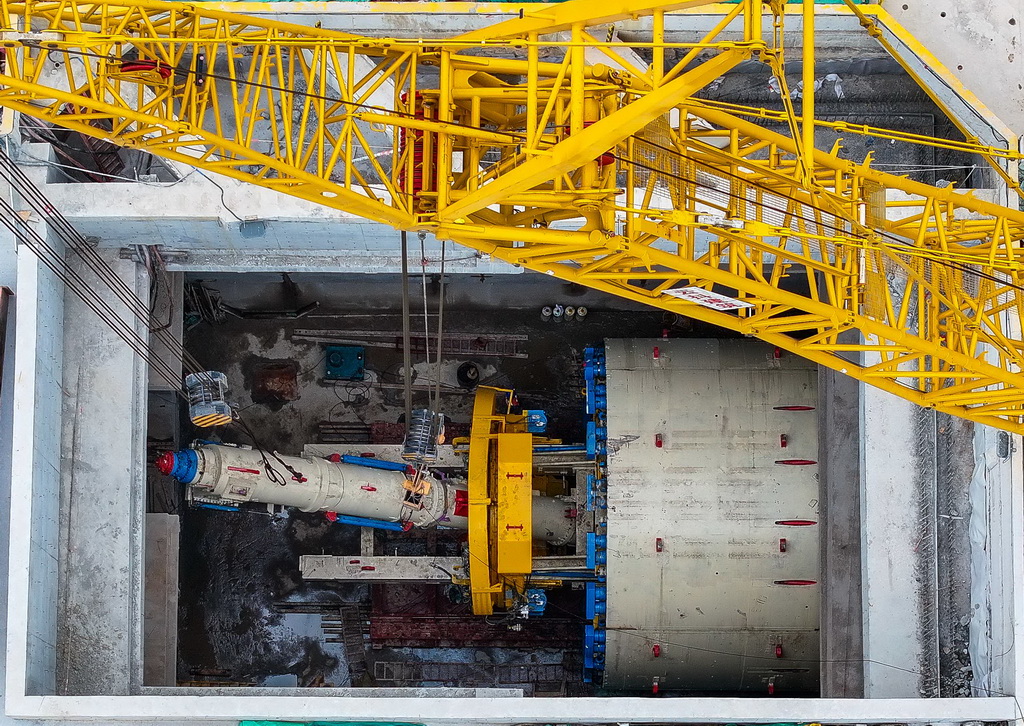 2月5日，建設者在南珠（中）城際十涌站盾構井吊裝右線盾構機主軸（無人機照片）。
