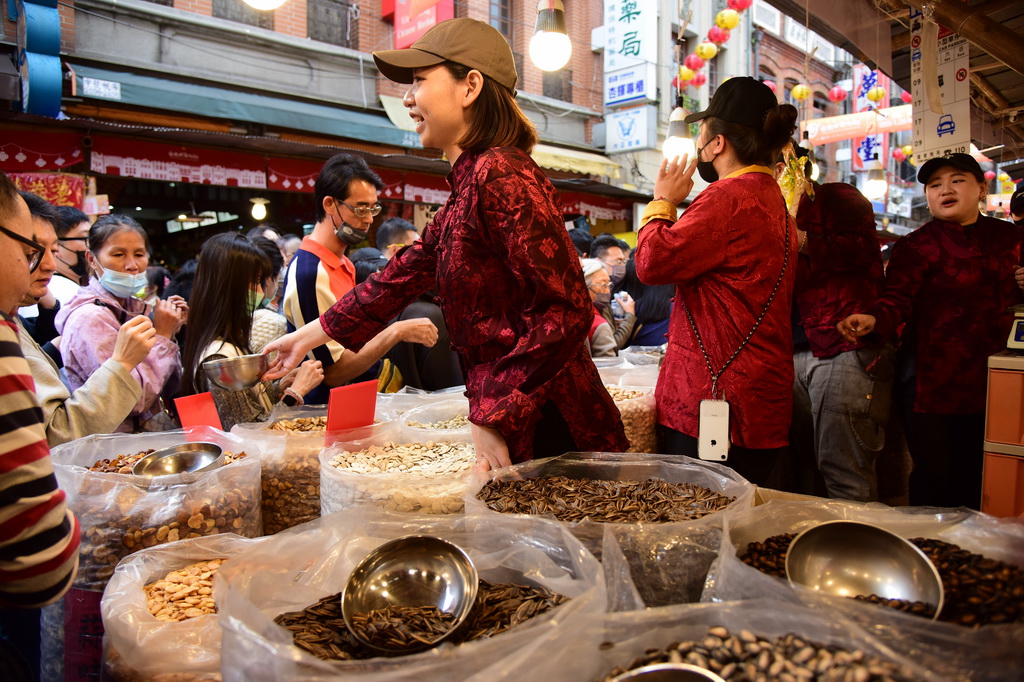 2月3日，在台北市迪化街，一處店鋪的店員在向採買年貨的顧客叫賣。新華社記者 陳鍵興 攝