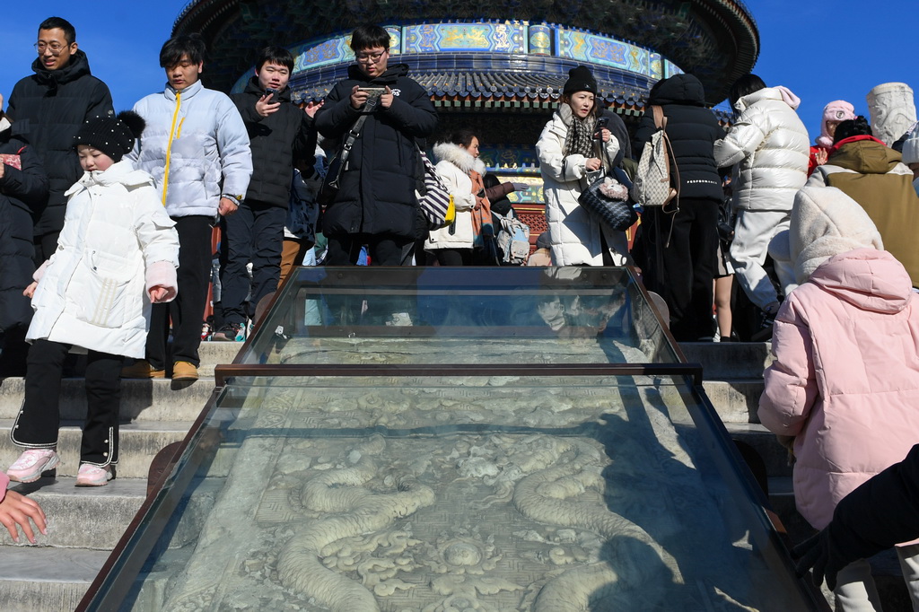 游客在天壇公園的石雕前游覽參觀，石雕上雕刻有兩條龍的形象（1月23日攝）。新華社記者 鞠煥宗 攝