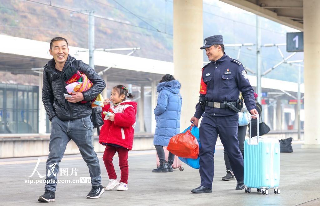 2月15日，在滬昆高鐵貴州銅仁南站，鐵路公安民警在幫助旅客搬運行李。胡攀學攝（人民圖片網）