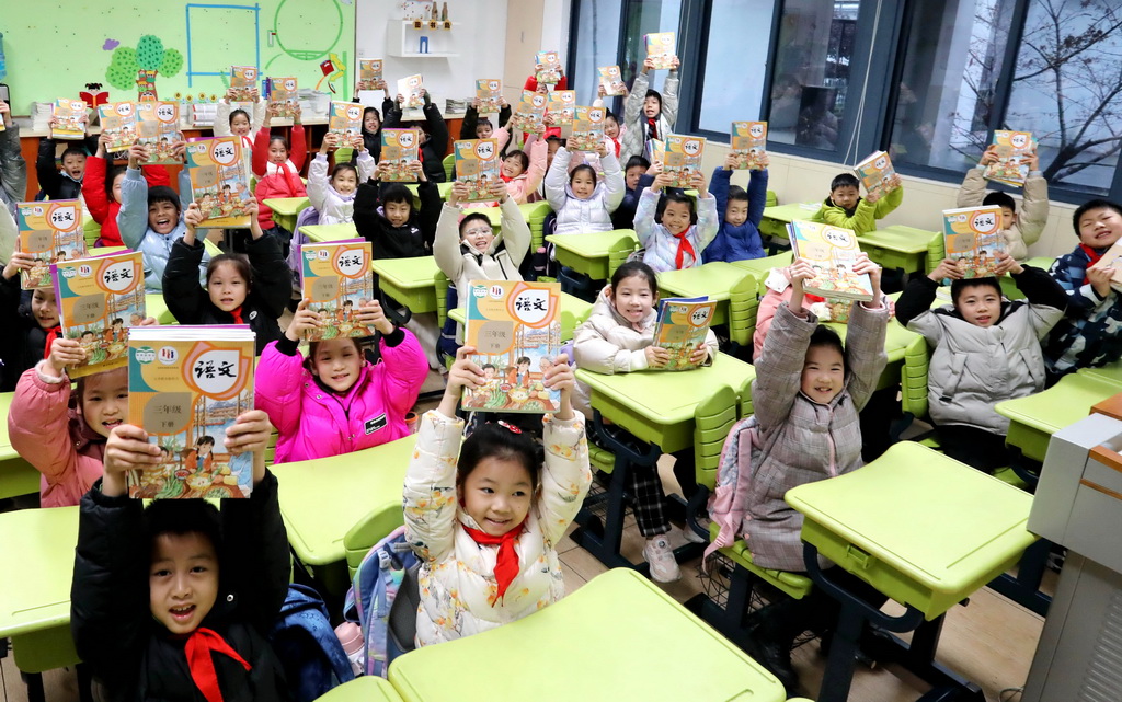 2月20日，在江蘇省蘇州市金閶實驗小學校，小學生展示領到的新學期課本。新華社發（杭興微攝）