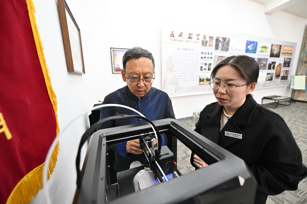 在雲岡研究院數字化保護中心，杭侃（左）和同事交流文創產品設計方案（2月25日攝）。新華社記者 詹彥 攝