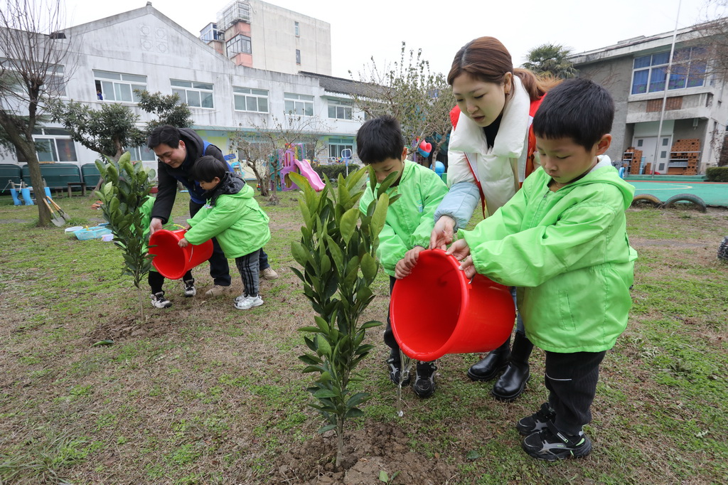 3月11日，江蘇省蘇州市姑蘇區新庄社區志願者帶著小朋友一起參加義務植樹活動。新華社發（杭興微攝）