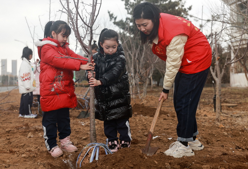 3月11日，在山東省榮成市府新小學周邊綠化點，志願者和小學生一起參加義務植樹活動。新華社發（李信君攝）