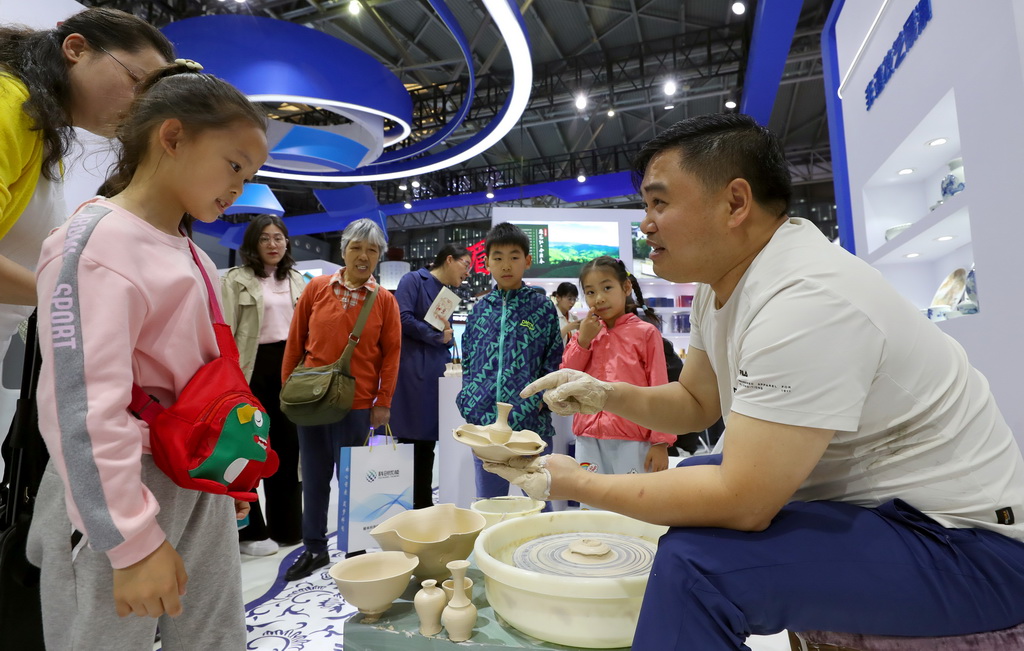 5月12日，江西景德鎮展台的工作人員（右）向參觀者介紹瓷器制作的步驟。