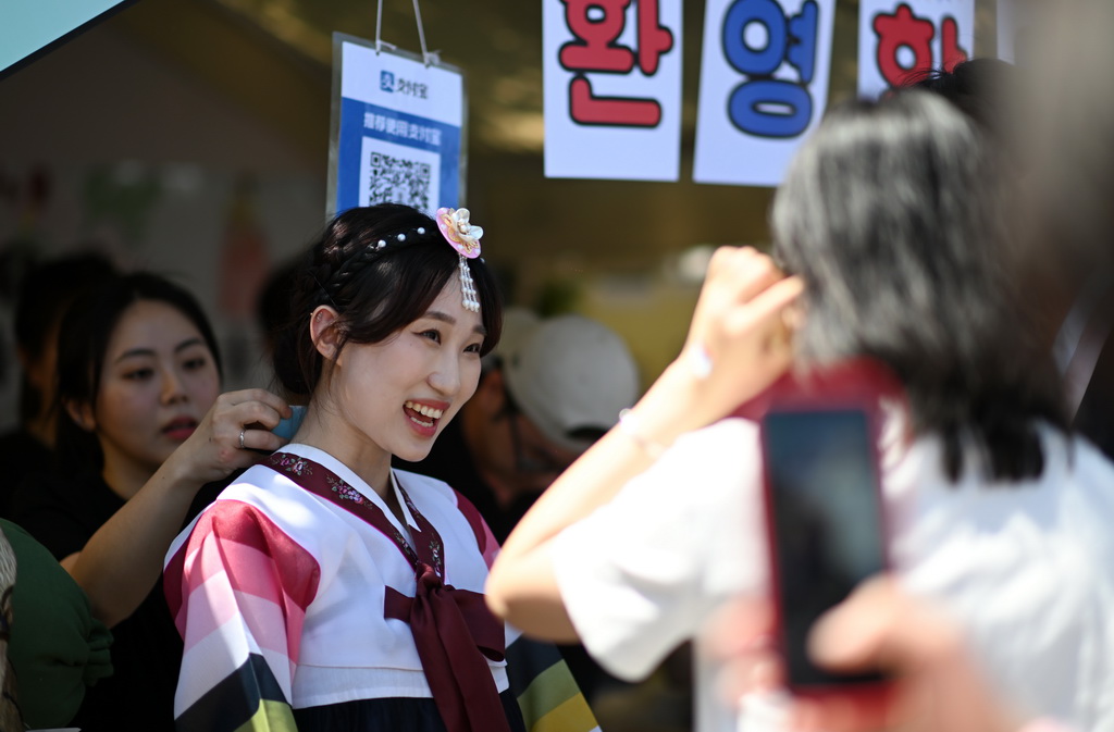 5月12日，在天津大學國際文化節，一名韓國留學生在展位前和觀眾交流。