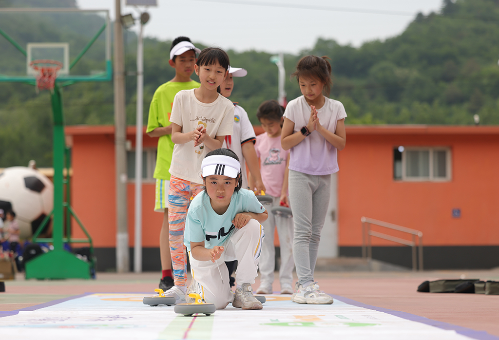 延慶區大庄科鄉中心小學迷你“奧運會”活動現場，學生們在進行旱地冰壺比賽。