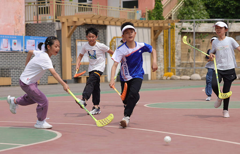 延慶區大庄科鄉中心小學迷你“奧運會”活動現場，學生們在進行旱地冰球比賽。