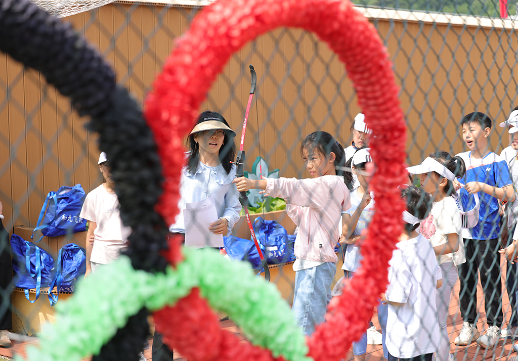 延慶區大庄科鄉中心小學迷你“奧運會”活動現場，學生們在進行趣味射箭比賽。