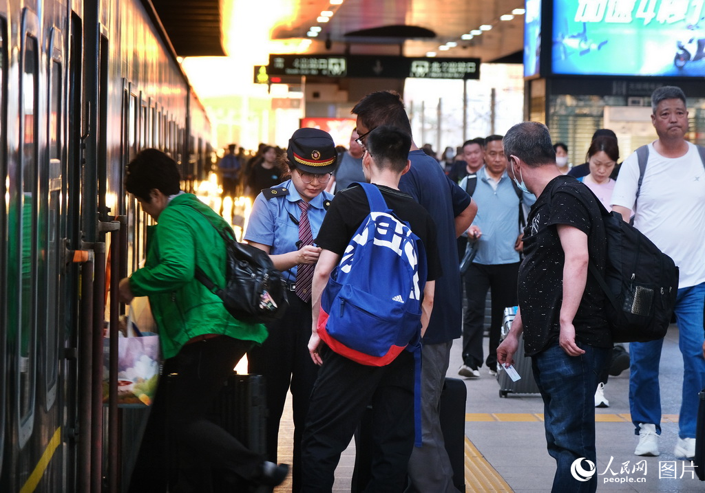 5月30日，北京至丹東K27/28次列車迎來了開行70周年途經天津站乘務人員在為旅客驗証乘車。