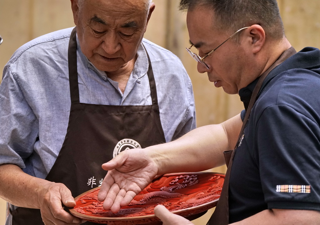 朱江（右）和父親朱慶元在雕漆工作室觀察烘干過程中的作品（5月30日攝）。