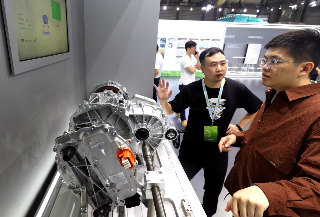 6月6日，一名工作人員（左）向參觀者介紹特斯拉汽車的電驅系統展品。