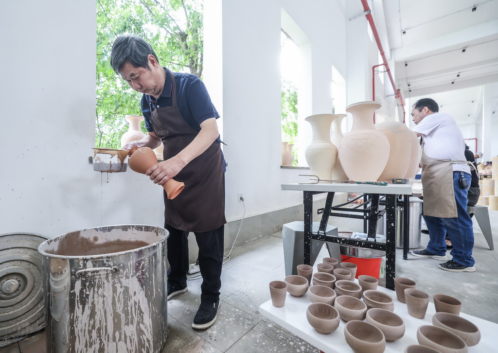 5月29日，中國陶瓷藝術大師、浙江省非物質文化遺產越窯青瓷傳承人孫邁華在龍窯旁給瓷坯上釉。