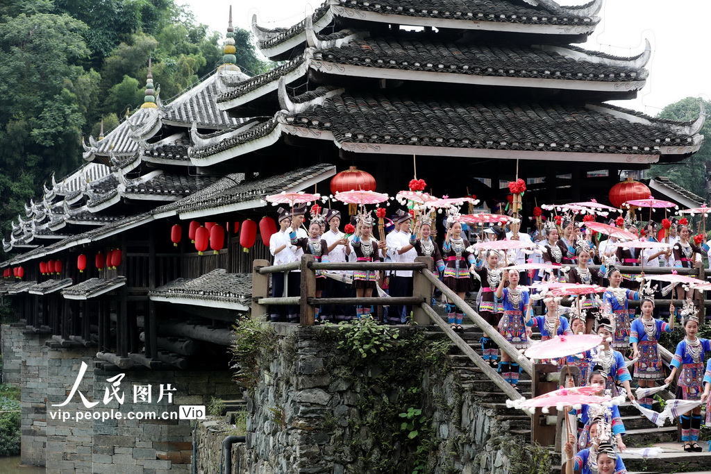 2024年6月8日，在廣西三江侗族自治縣林溪鎮的程陽八寨，村民在風雨橋頭迎接游客。