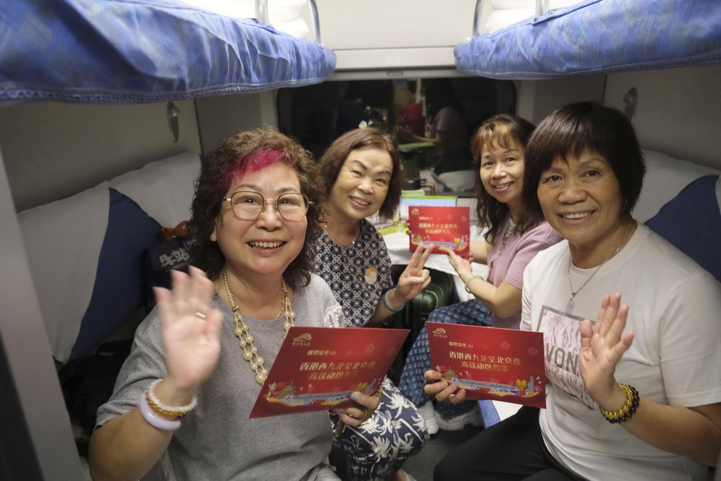 6月15日，旅客在香港西九龍至北京西D910次高鐵動臥列車上展示首班車紀念品。新華社記者 王申 攝
