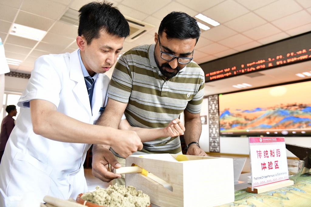 6月18日，在青岛西海岸新区中医医院，青岛大学国际教育学院留学生（右）在体验艾灸棒制作。新华社记者 郭绪雷 摄
