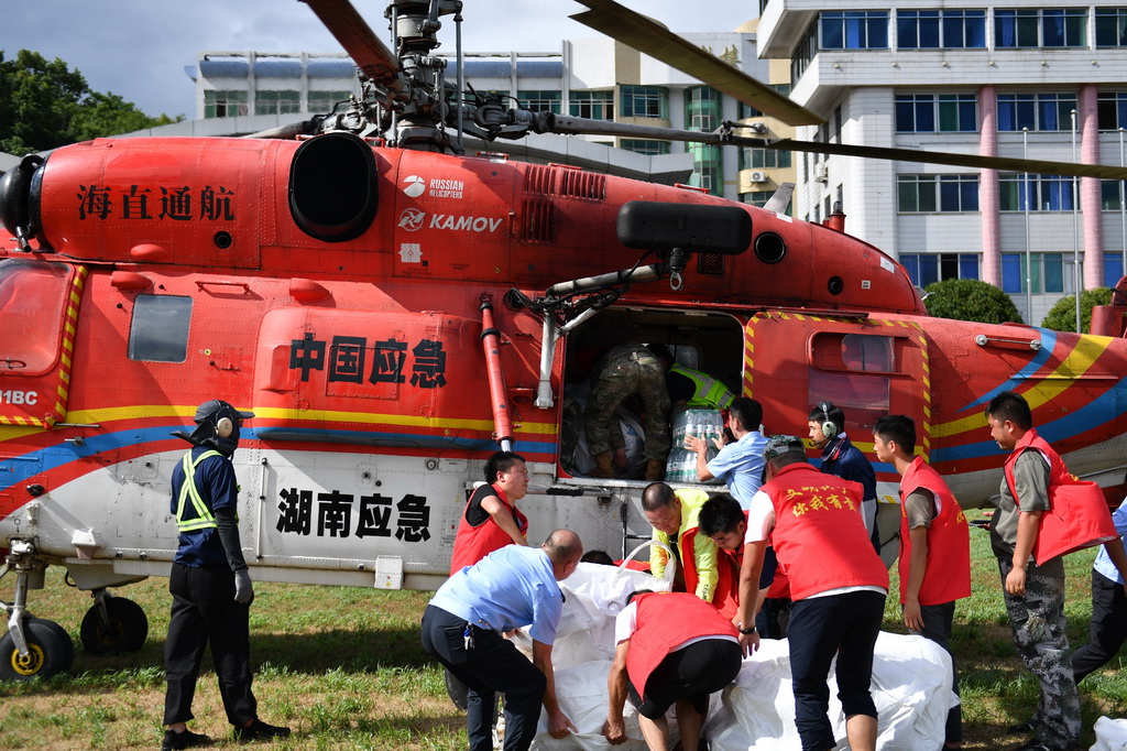 7月29日，在资兴市第一中学，志愿者和工作人员将准备投放至受灾乡镇的生活物资搬运上直升机。