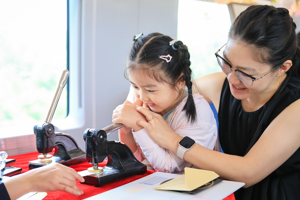 8月8日，在G132次列車上，家長和孩子一起體驗鋼印制作書簽。