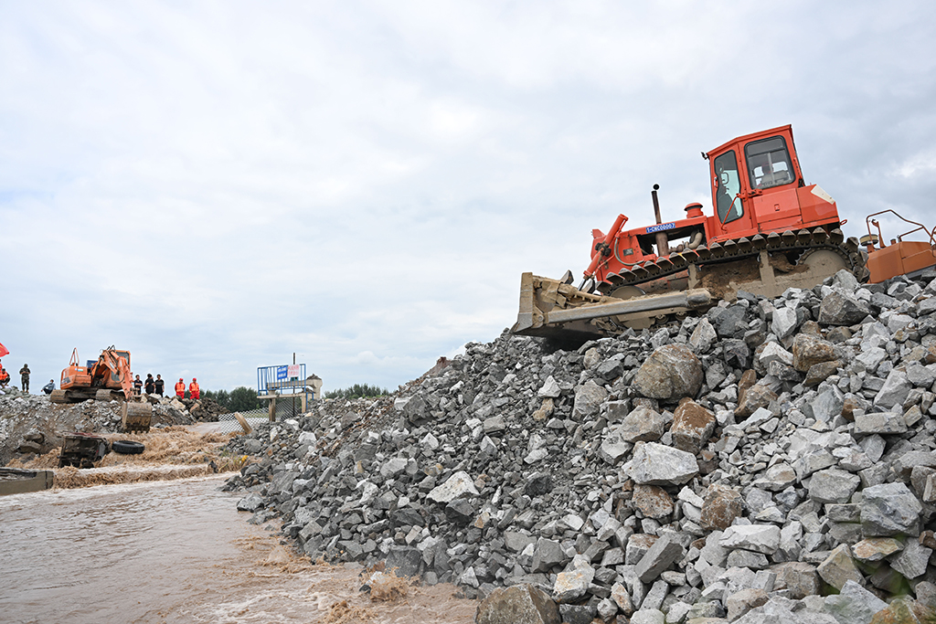 8月14日，大型機械在內蒙古赤峰市老哈河堤防潰口搶險現場作業。