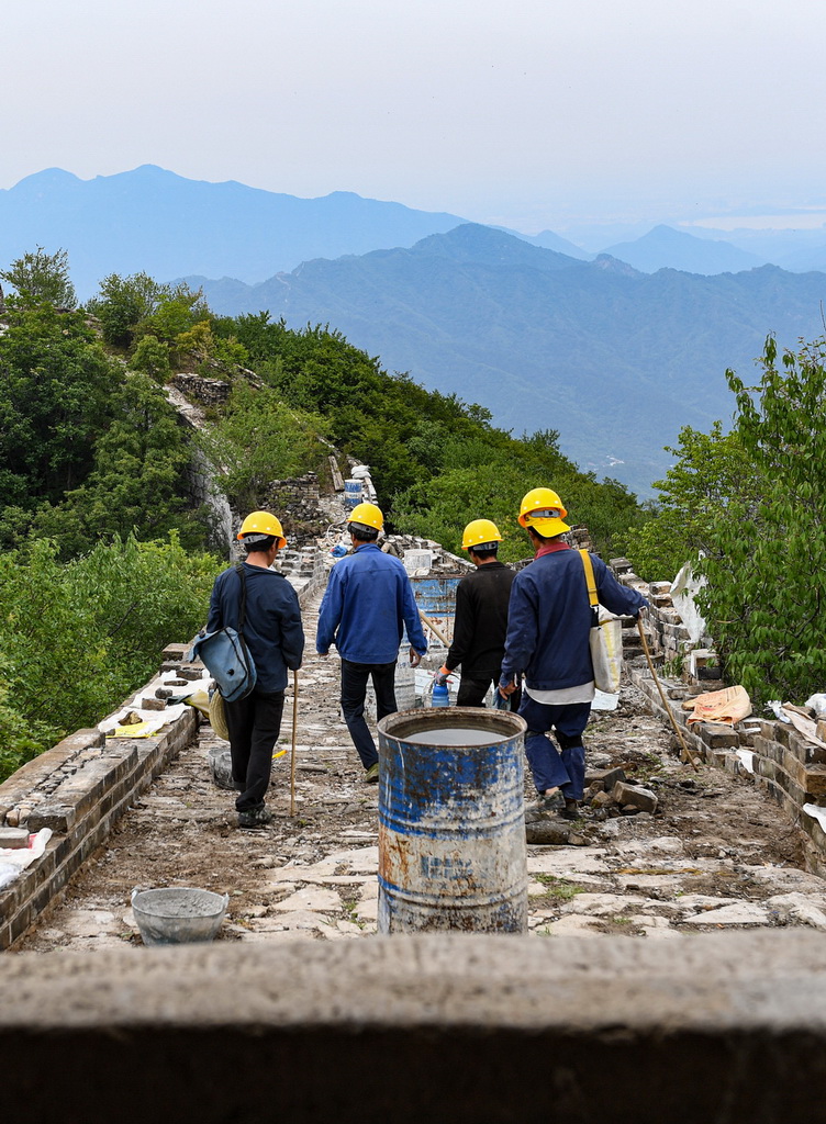 在箭扣長城122號敵台東側牆體修繕施工現場，工人們結束上午的工作，准備離開去吃午飯（7月2日攝）。