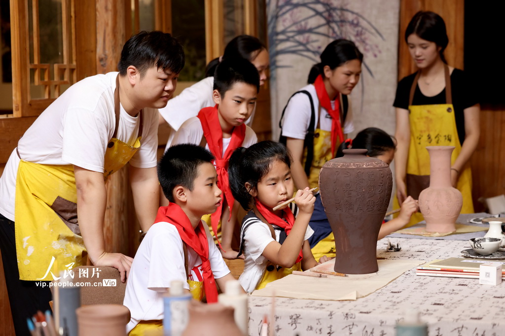 8月19日，工藝美術師在指導學生制作烏金紫砂陶藝術品。