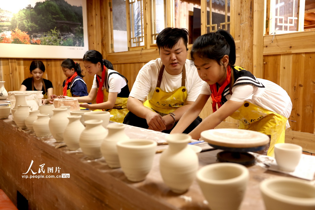 8月19日，工藝美術師在指導學生制作烏金紫砂陶藝術品。