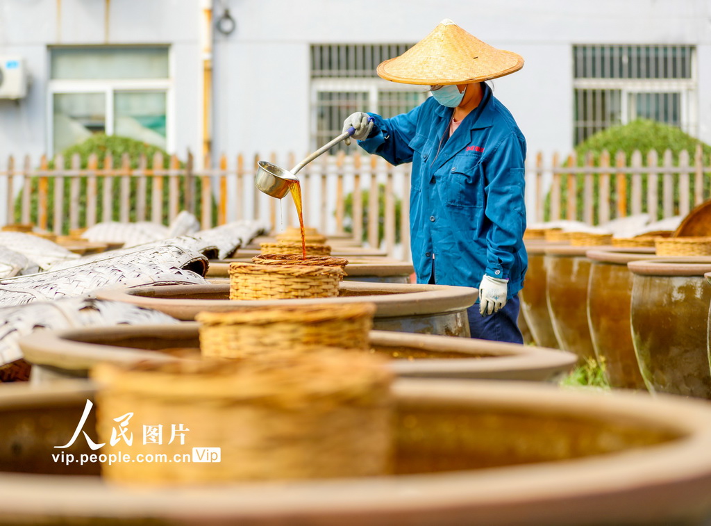 2024年9月21日，山東滕州市一家醬醋食品有限公司的工人在晾晒場上澆淋晒制醬油。