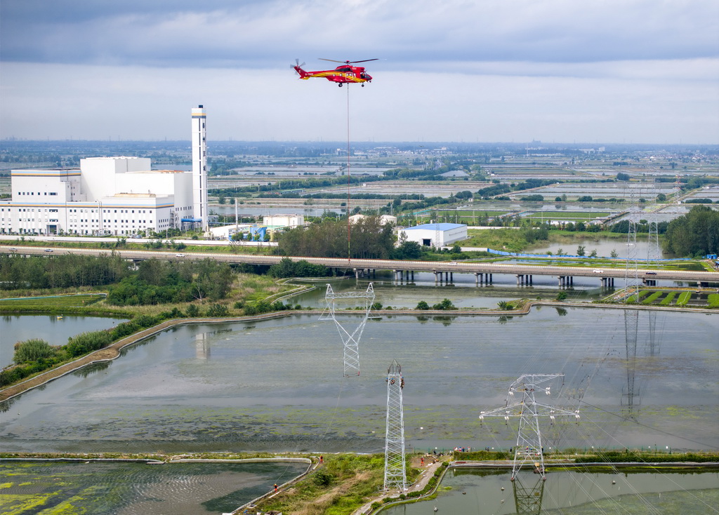 9月24日，直升機在江蘇省興化市昌榮鎮上空協助鐵塔架設作業（無人機照片）。新華社發（湯德宏攝）