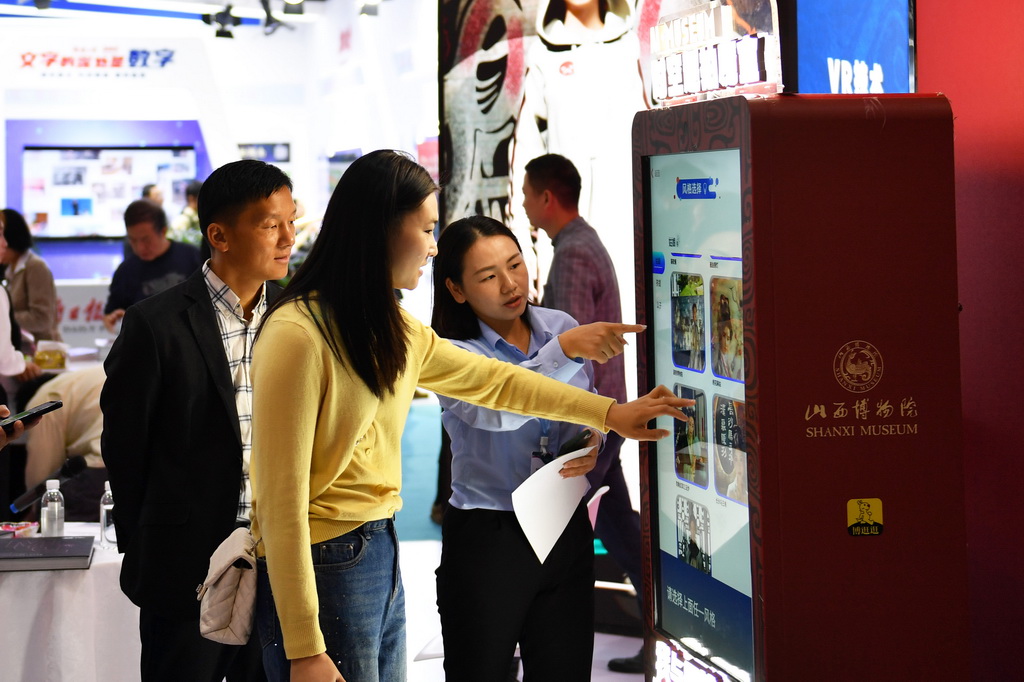 10月15日，一名参观者（中）在2024中国新媒体技术展上体验一款AI照片生成设备。