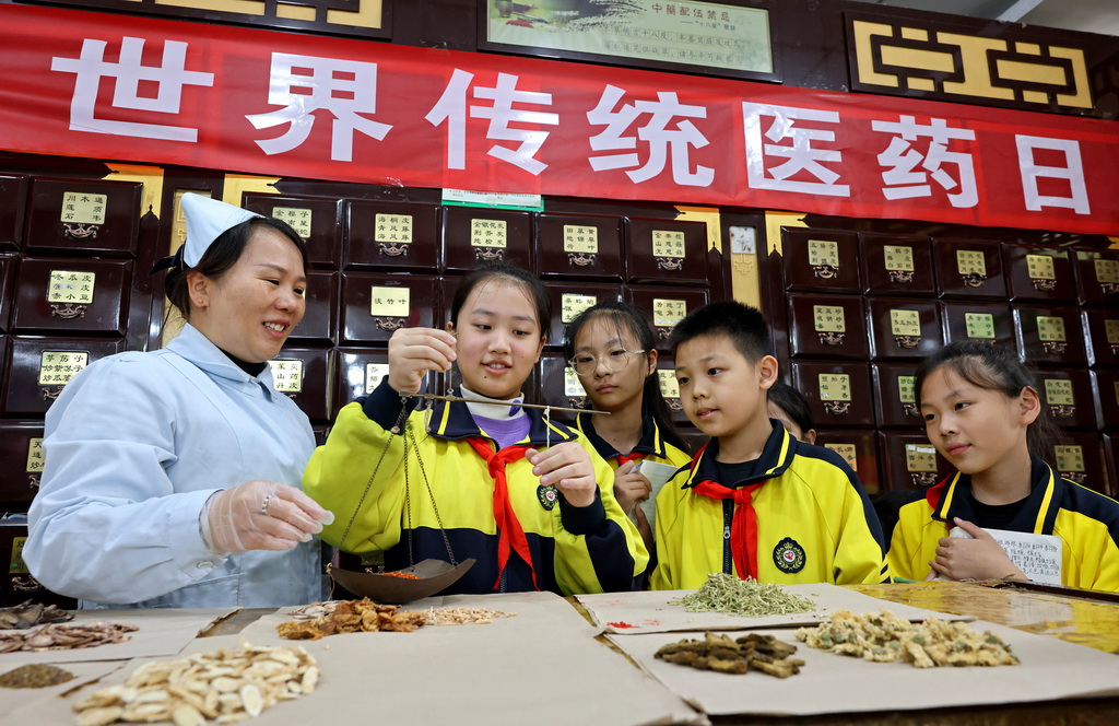 10月22日，山东省枣庄市文化路小学学生在一家中药店体验称量中草药。新华社发（孙中喆摄）