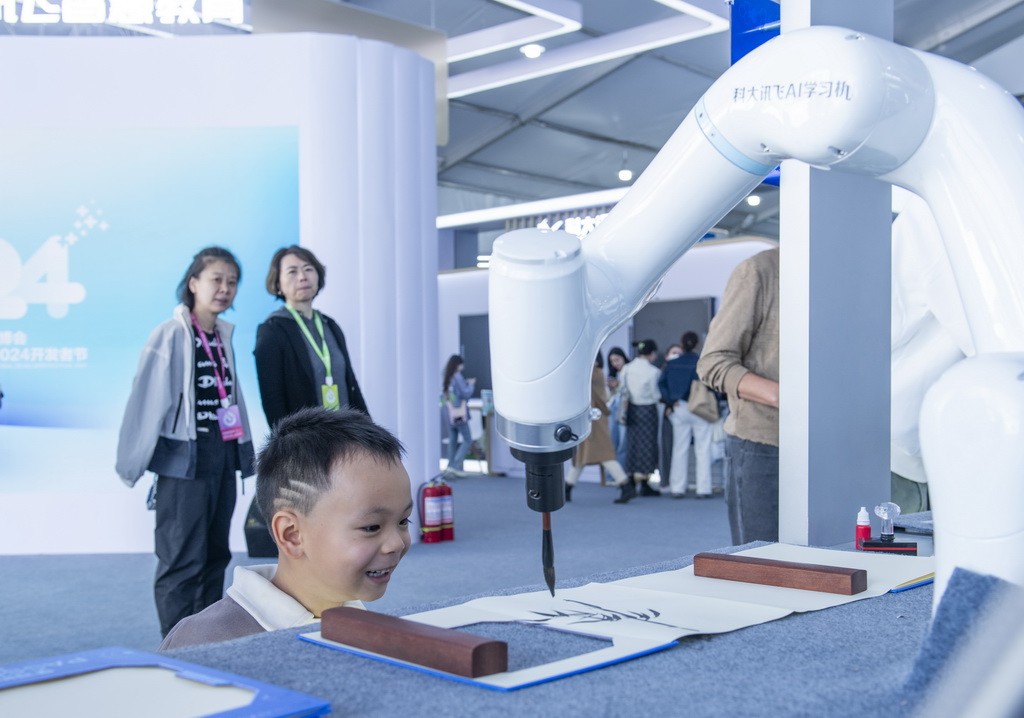 10月24日，一名儿童在第七届世界声博会上参观一款国画书法机器人。