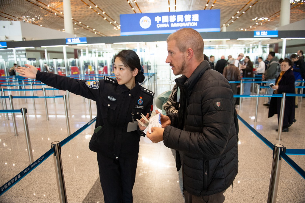 12月4日，邊檢民警在北京首都機場三號航站樓邊檢入境現場引導外國游客。新華社記者 陳鐘昊 攝