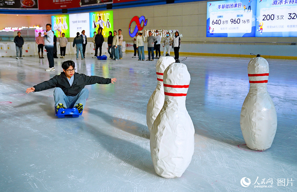 11月29日，江西省赣州市章贡区的一家室内真冰滑冰场，冰雪运动爱好者在参与体验趣味冰上运动会“冰上保龄球”项目。人民网 朱海鹏摄