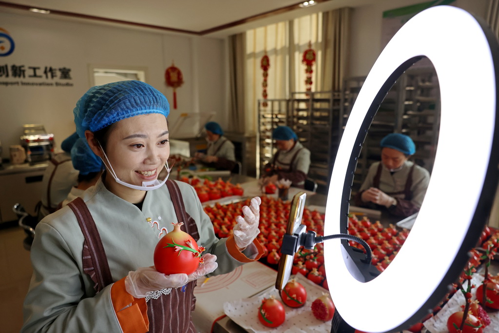 12月29日，在山东省枣庄市“红石榴”喜馍制作工坊，民间艺人通过网络直播介绍“红石榴”喜馍制作方法。新华社发（孙中喆摄）