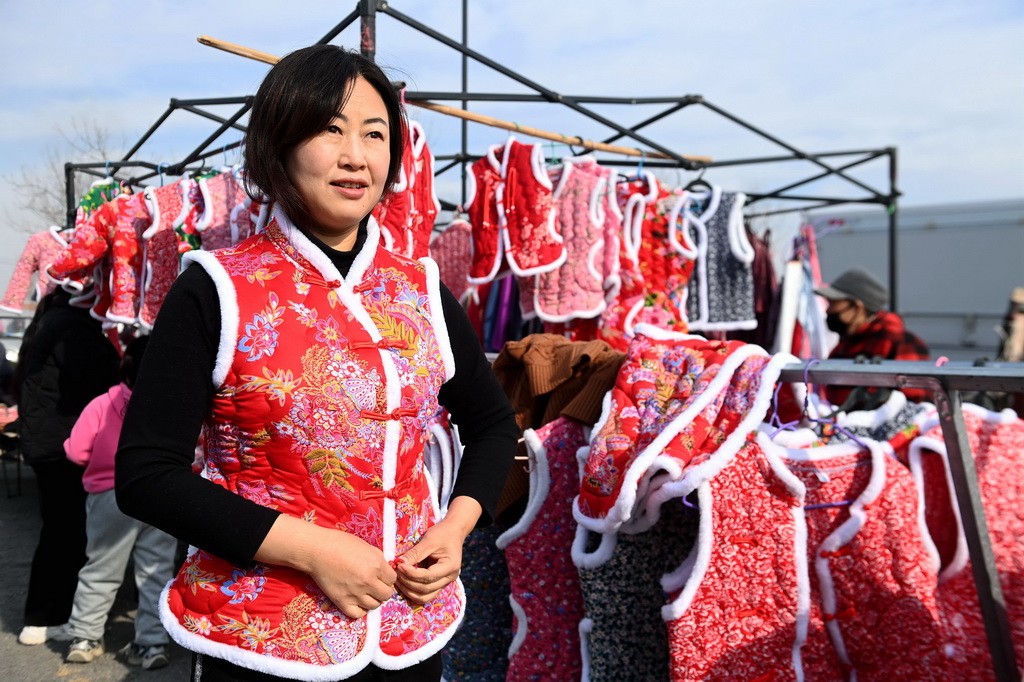 12月29日，在山東青島西海岸新區泊裡大集，一名消費者在試穿新年喜慶服裝。新華社發（俞方平攝）