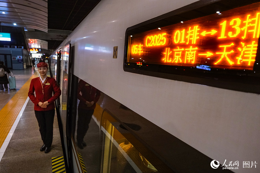 12月30日，乘务人员在北京南开往天津的C2025次列车立岗迎接旅客乘车。