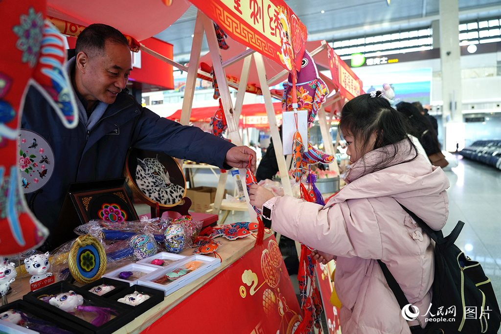 2025年春运首日，“多彩民俗迎春运”活动在西宁火车站候车大厅内举办，刺绣展柜上各种各样的非遗和文创产品引得旅客驻足围观。人民网记者 杨启红摄