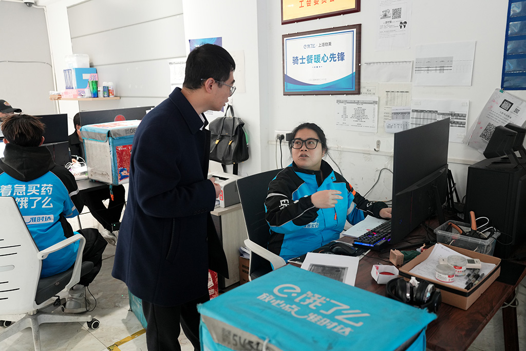 胡东方（右二）在浙江省温州市一家外卖骑手站点与工作人员交流（2025年2月18日摄）。