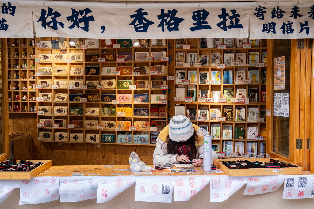 一名游客在雲南省迪慶州香格裡拉市獨克宗古城寫明信片(2025年3月7日攝)。