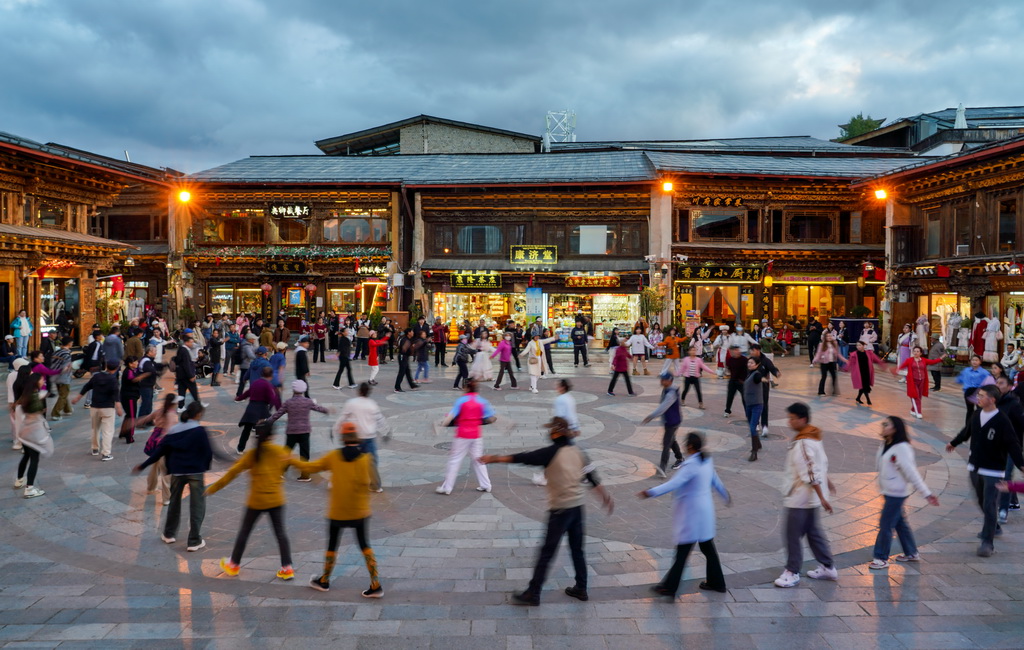 游客和當地群眾在雲南省迪慶州香格裡拉市獨克宗古城裡一起跳舞(2024年9月27日攝)。