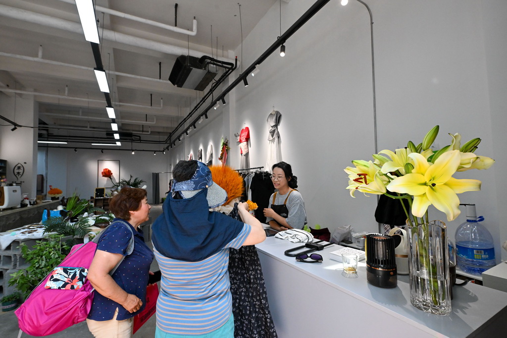 在天津天拖片區城市更新項目內，市民在老廠房改造的商業街區裡購物（5月30日攝）。