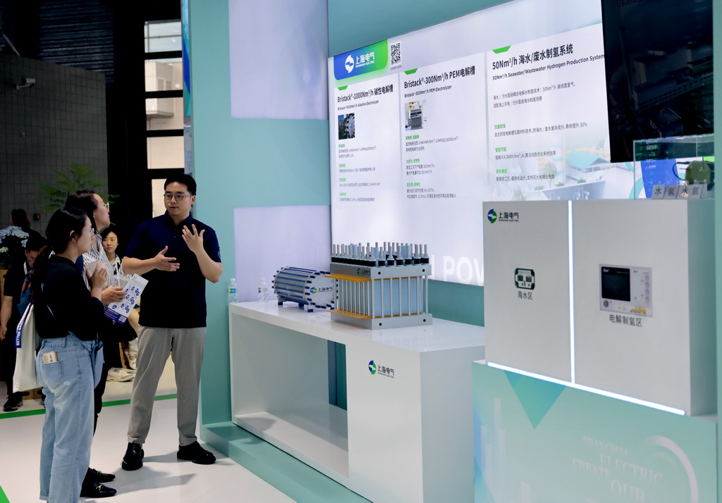 6月5日，工作人员（右）在向参观者介绍电解槽制氢设备。