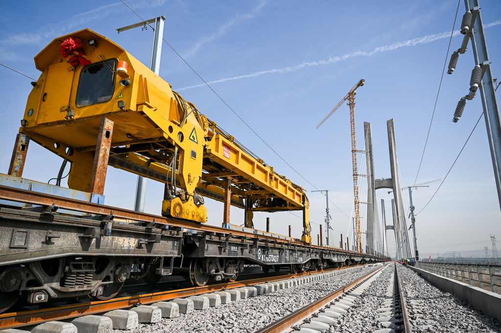 6月6日，在包银高铁乌海黄河特大桥，工人操作工程机械进行铺轨作业。新华社记者 连振 摄