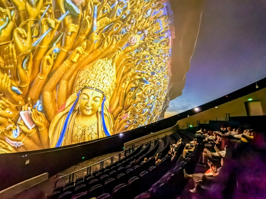 6月24日,游客在大足石刻景区观看8K球幕电影。