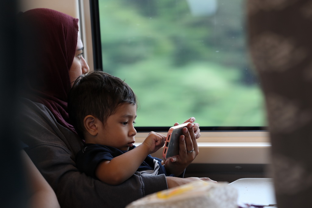 6月19日，一名乘客帶孩子坐在行駛中的雅萬高鐵車廂內。